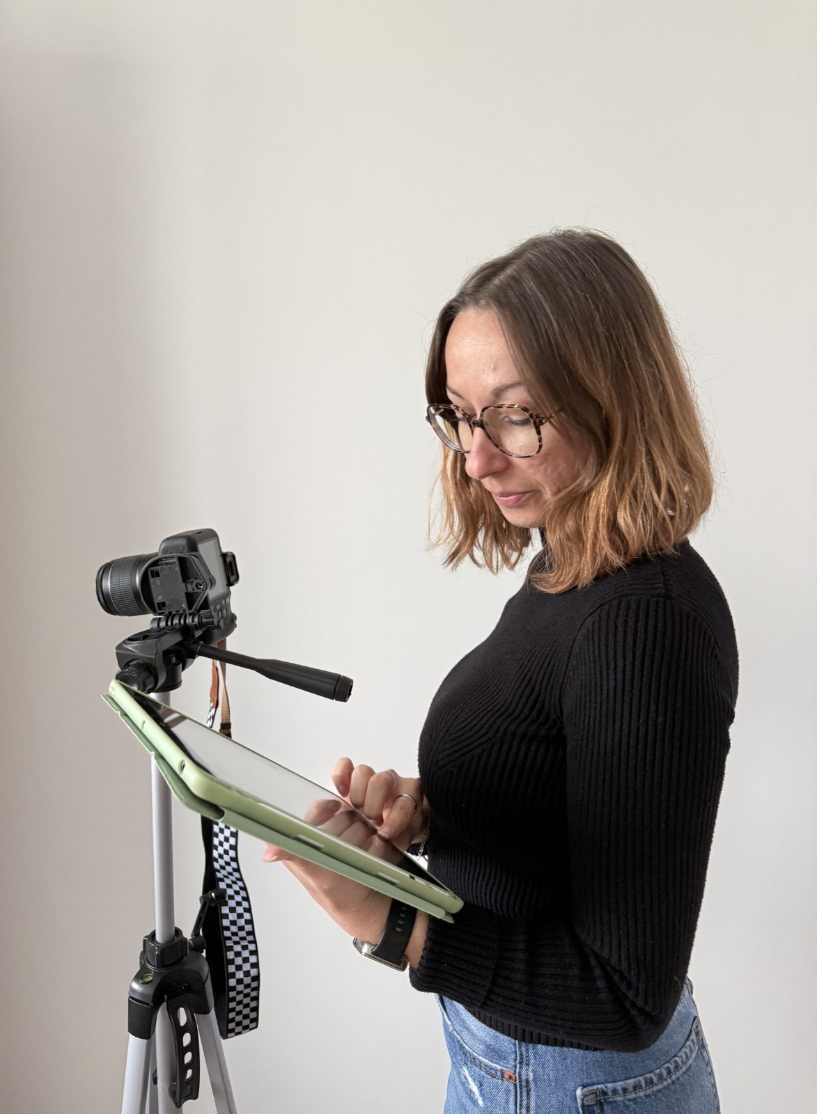 Chloé prépare des contenus sur sa tablette, à côté de son appareil photo